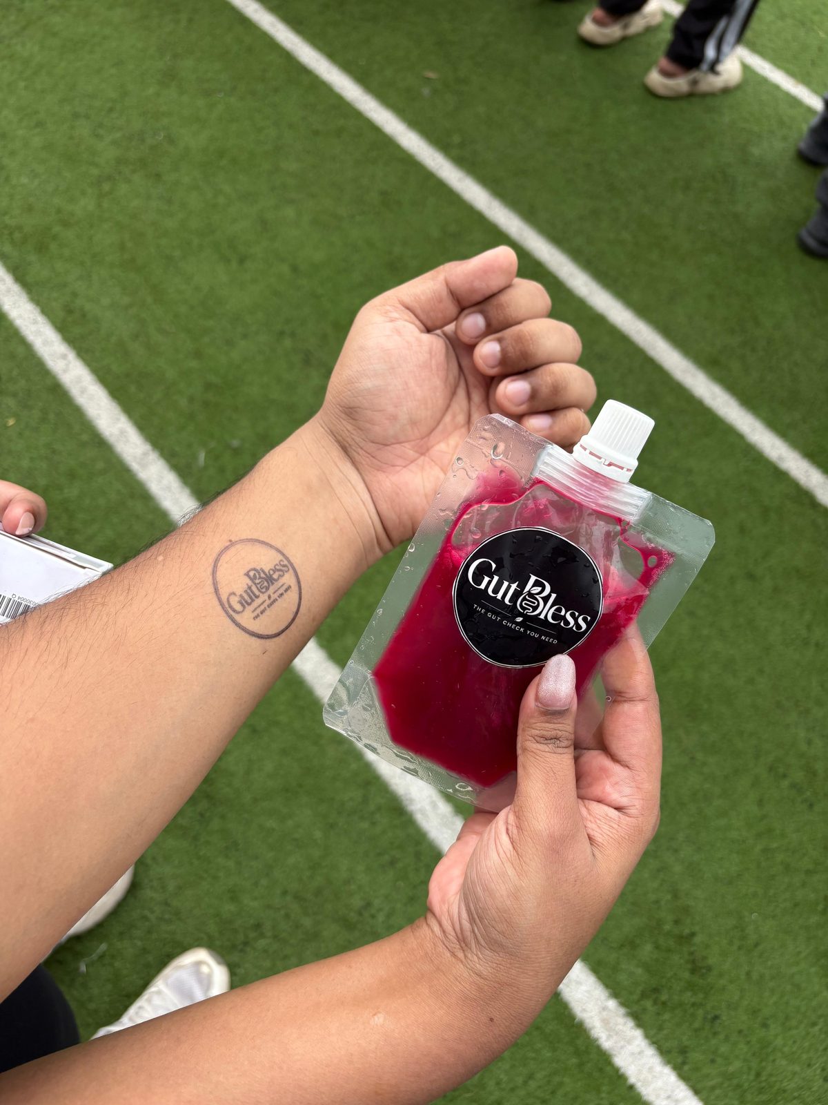 A GutBless brand stamp on a runner's wrist next to a fresh juice pouch
